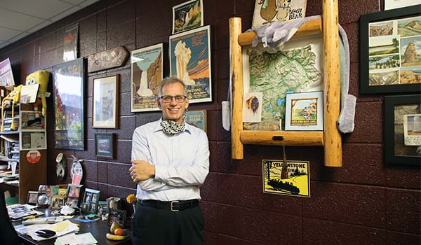 Steven Ropski stands in front of many biology and environmental science photos, framed and hung on the cinder block wall in his office.